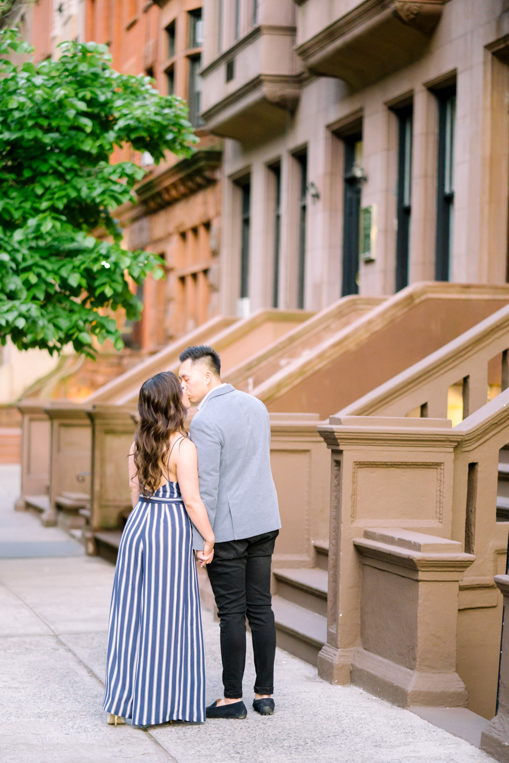 A couple in New York's Upper East Side for engagement photos with brownstone houses